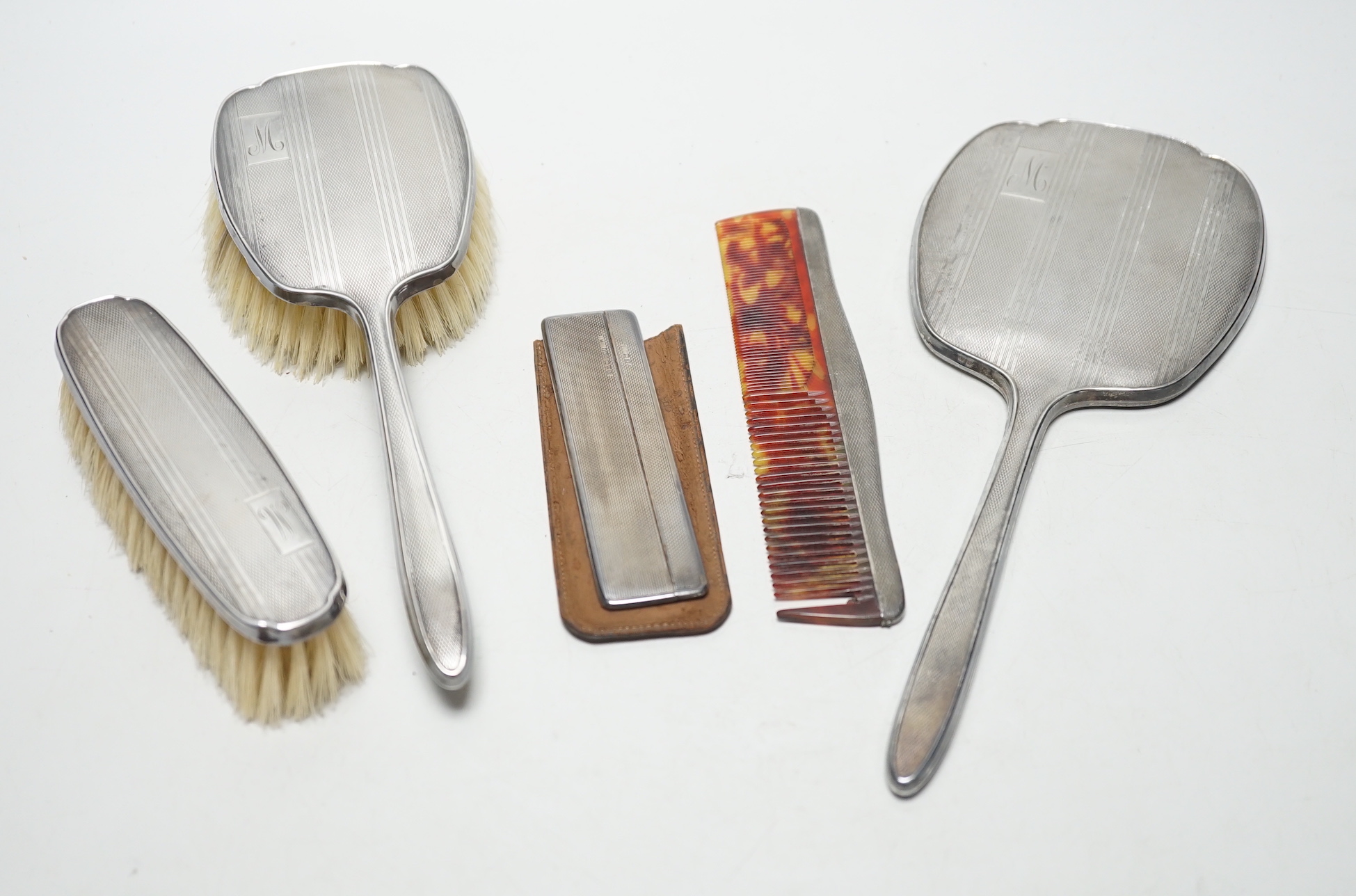 A George V silver backed four piece dressing table set, Birmingham, 1934 and one other silver cased comb.